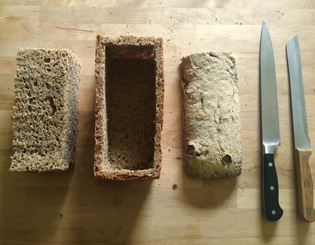 loaf of bread on a cutting board with the crust and top intact, but the middle removed in a block