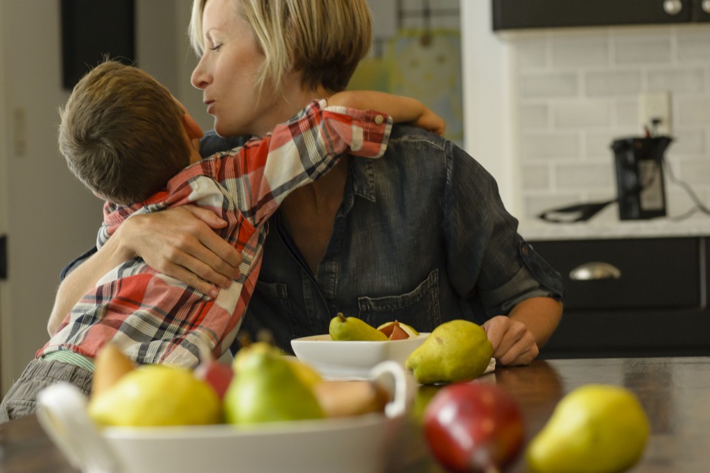 Mother and sun snuggling in the kitchen with an assortment of colorful, fresh pears