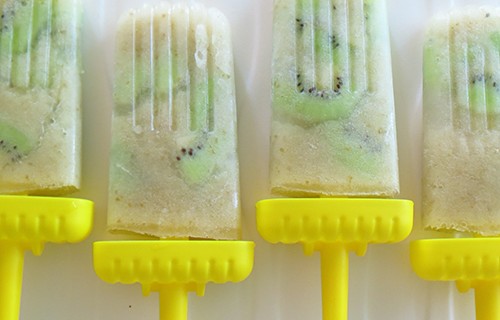 Creamy pear popsicles with chunks of kiwi and yellow sticks