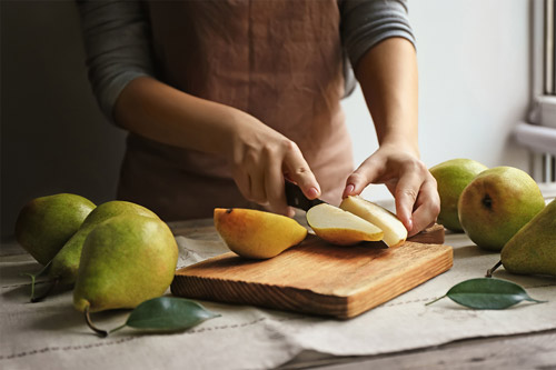 A person cutting pears on a cutting board
